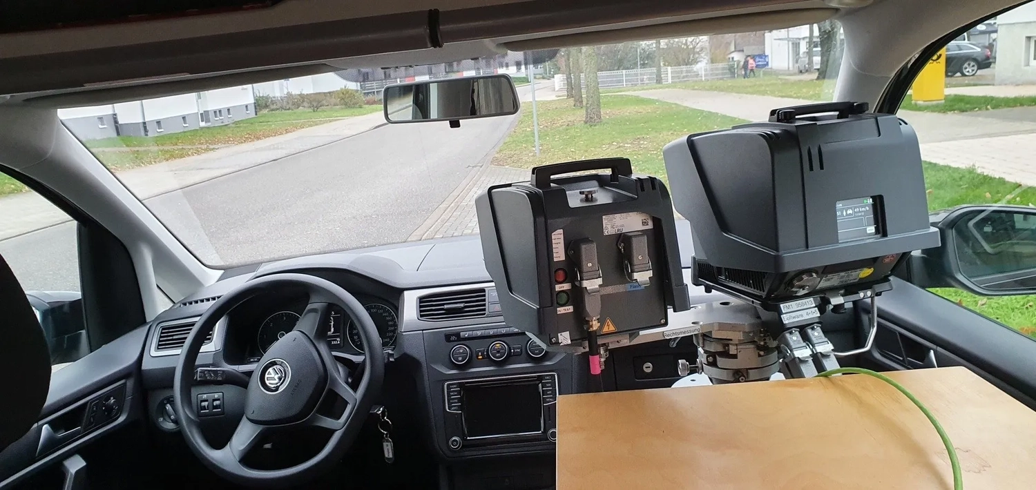Interior of a Volkswagen car with a large mounted electronic device on the dashboard and a wooden board beside it.