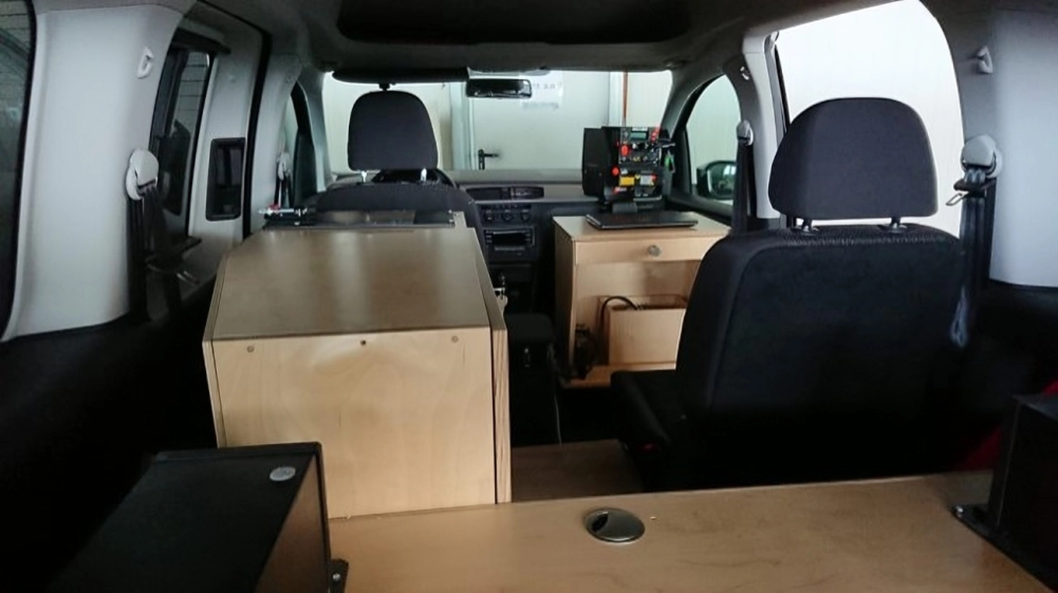 Radarrent GmbH - Verkehrsüberwachung - Innenansicht eines Fahrzeugs mit zwei schwarzen Vordersitzen und Holzkisten, die anstelle der Rücksitze eingebaut sind