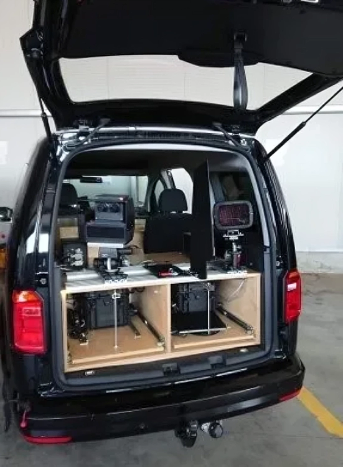 Radarrent GmbH – Verkehrsüberwachung – Offener Heckbereich eines schwarzen Transporters mit maßgefertigten Holzfächern und eingebauter Elektronik im Inneren